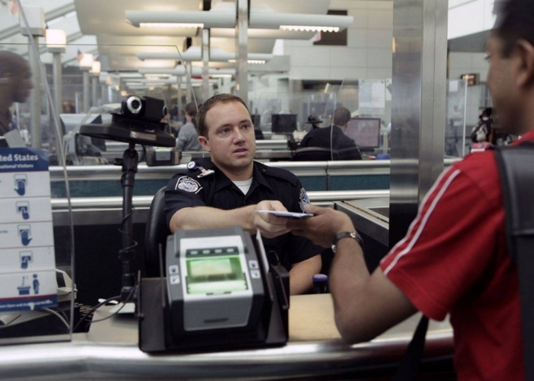Du khách trình hộ chiếu và visa cho nhân viên hải quan Mỹ tại quầy nhập cảnh